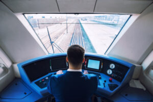 Shot of train cockpit interior with driver sitting and driving train.